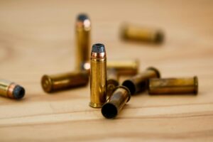 Detailed view of brass bullet shells scattered on a wood background.